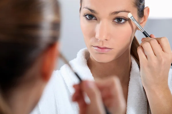 Mujer aplicando maquillaje en el baño —  Fotos de Stock