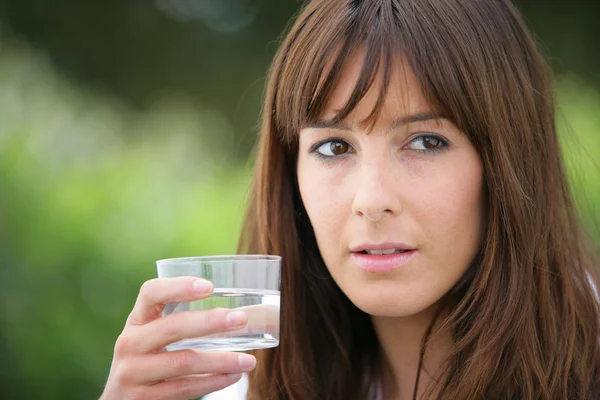Bruneta drží sklenici vody — Stock fotografie