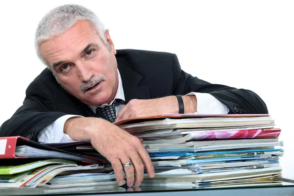 Affärsman som ligger över en hög med dokument — Stockfoto