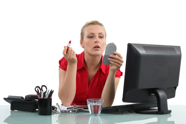 Blond woman applying lipstick in office — Stock Photo, Image