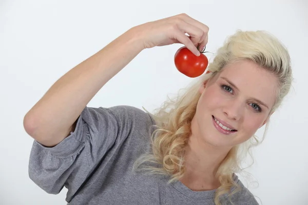 Sorrindo mulher loira segurando tomate no fundo branco — Fotografia de Stock