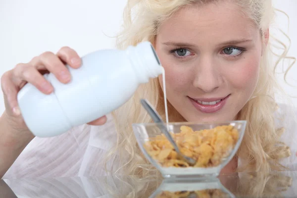 Frau gießt Milch auf Cornflakes — Stockfoto