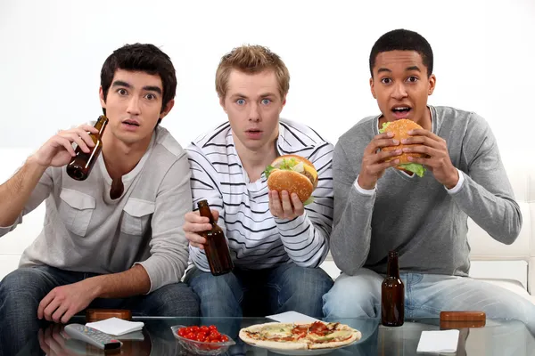 Amigos do sexo masculino comer hambúrgueres e assistir esporte na TV — Fotografia de Stock