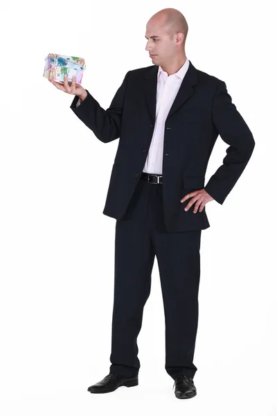 Businessman with a house made of money — Stock Photo, Image