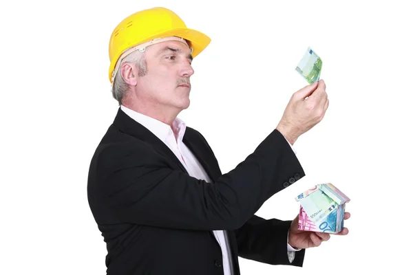 Businessman holding a little house made of bills — Stock Photo, Image