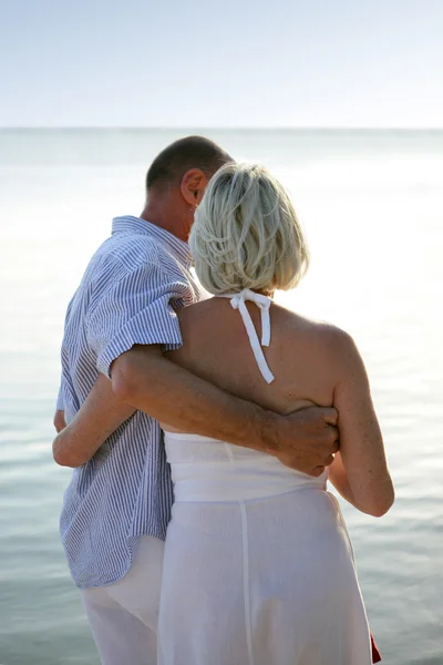 Casal mais velho caminhando ao longo de uma praia — Fotografia de Stock