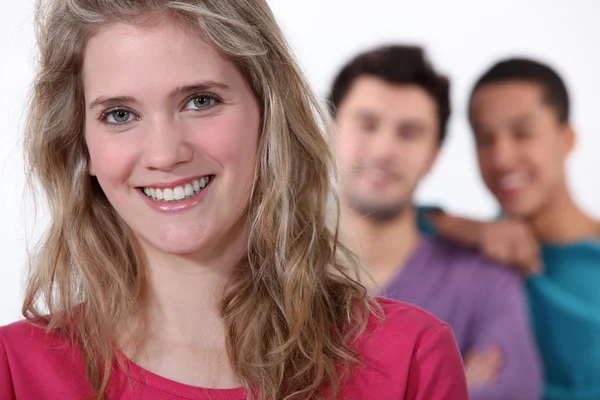 Smiling young woman with lads in the background — Stock Photo, Image