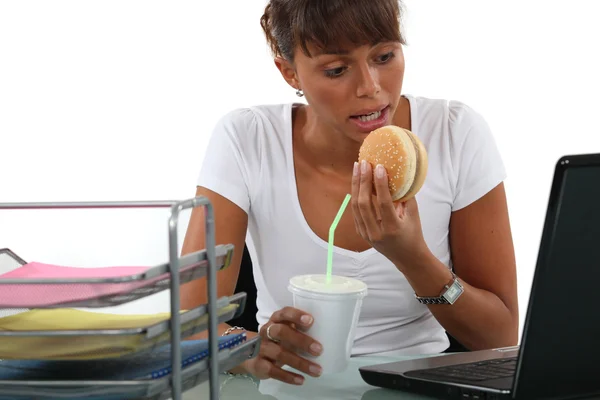 Trabajadora de oficina almorzando rápido frente a su computadora — Foto de Stock
