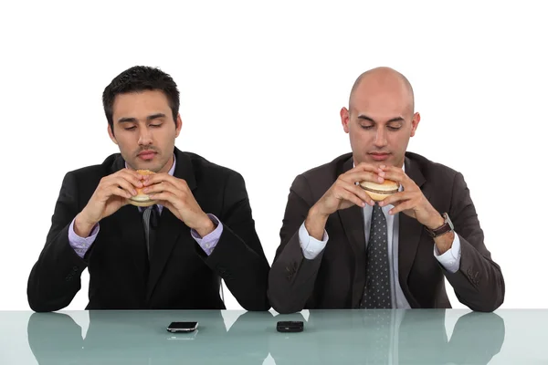 ハンバーガーを楽しむ 2 人のビジネスマン — ストック写真