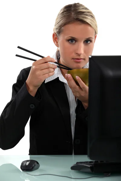 Kobieta siedzi na swoim komputerze jedzenia pałeczkami — Zdjęcie stockowe