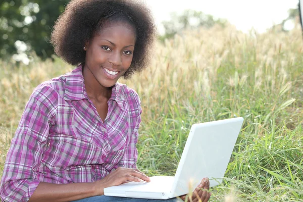 Woman sat in field using laptop computer — Stock Photo, Image