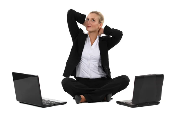 Blonde Geschäftsfrau saß im Schneidersitz mit zwei Laptops — Stockfoto