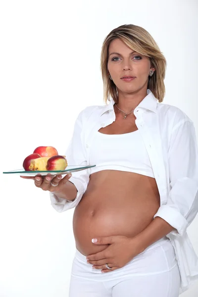 Těhotná žena drží talíř jablek — Stock fotografie