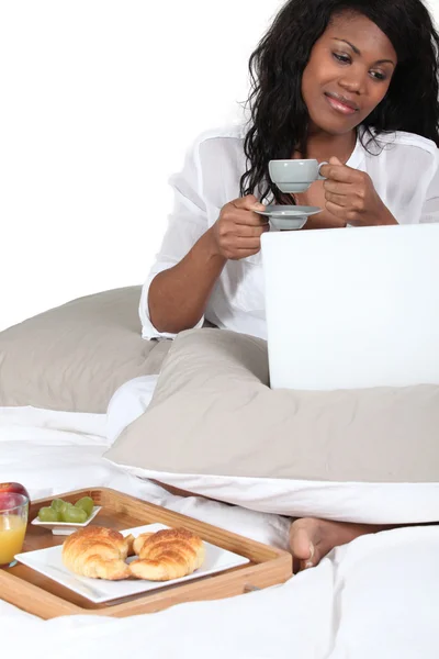 Kvinna med frukost i sängen och kontrollera sin e-post — Stockfoto