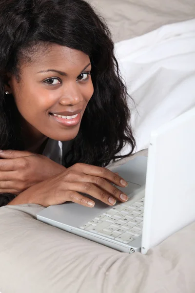 Žena se baví s laptopem v posteli — Stock fotografie
