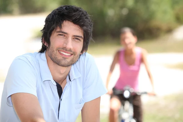 Muž na koni na kole venku a rozmazané pozadí a žena na koni na kole — Stock fotografie