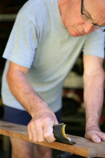 Senior Heimwerker schleift ein Brett aus Holz — Stockfoto