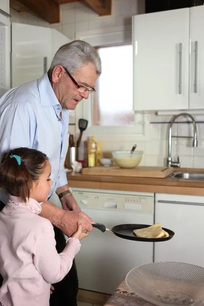 Liten flicka gungade pannkakor med hennes farfar — Stockfoto