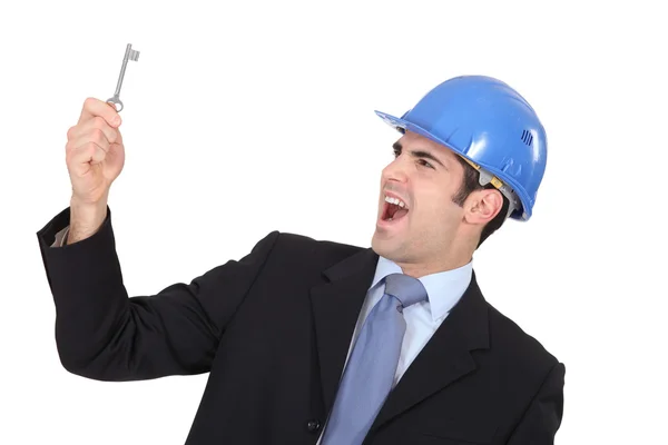 Delighted businessman in a hardhat with a doorkey — Stock Photo, Image