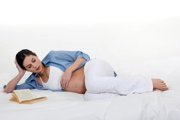 Mulher grávida lendo na cama — Fotografia de Stock