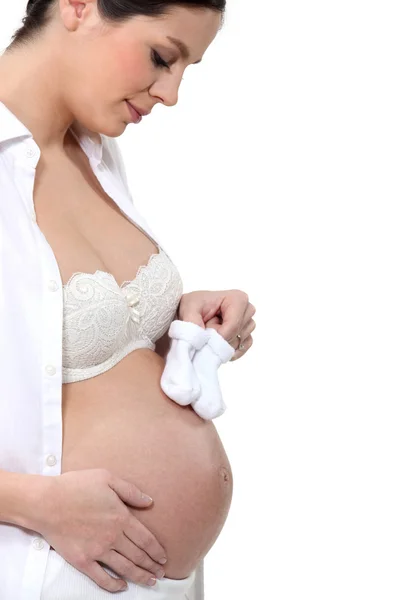 Jonge zwangere vrouw met bootees rust op blote buik — Stockfoto