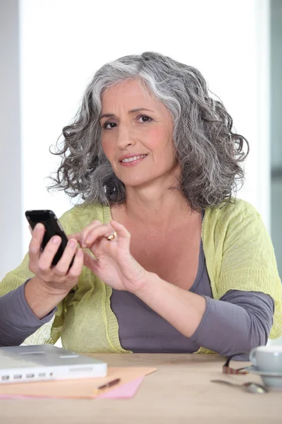 Mulher de cabelos grisalhos enviando mensagem de texto — Fotografia de Stock