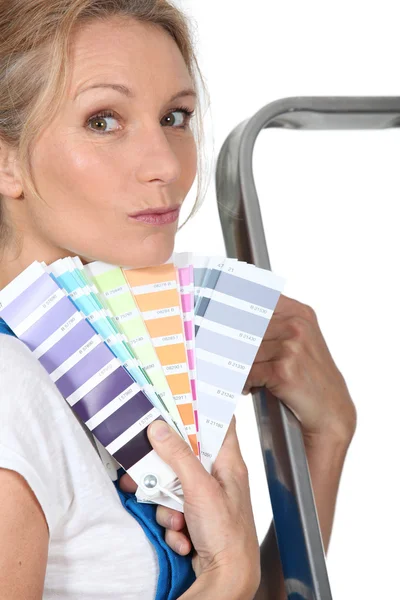 Woman stood by ladder holding paint swatches — Stock Photo, Image