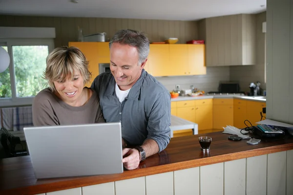 Ζευγάρι χρησιμοποιώντας ένα φορητό υπολογιστή στην κουζίνα — Φωτογραφία Αρχείου