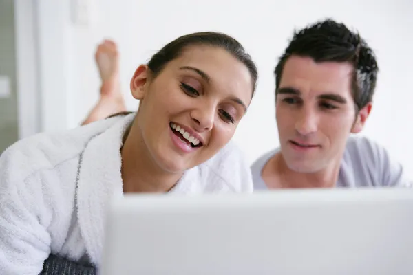 Giovane coppia guardando un computer portatile a letto — Foto Stock