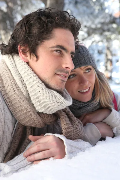 Attractive couple laying in the snow — Stock Photo, Image
