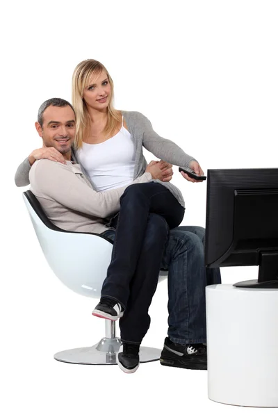 Couple sitting in a chair watching television — Stock Photo, Image