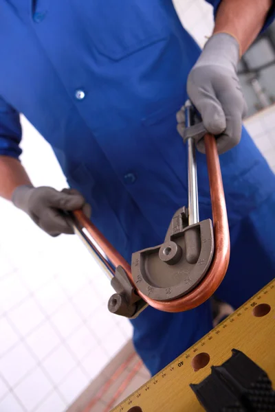 Trabajador usando una herramienta para doblar un tubo de cobre — Foto de Stock