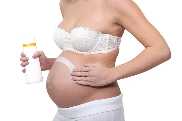 Беременная женщина намазывает крем на живот — стоковое фото