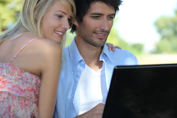 Par i park med bärbar dator — Stockfoto
