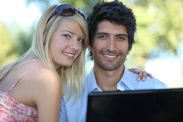 Молода пара використовує ноутбук комп'ютера в парку — стокове фото