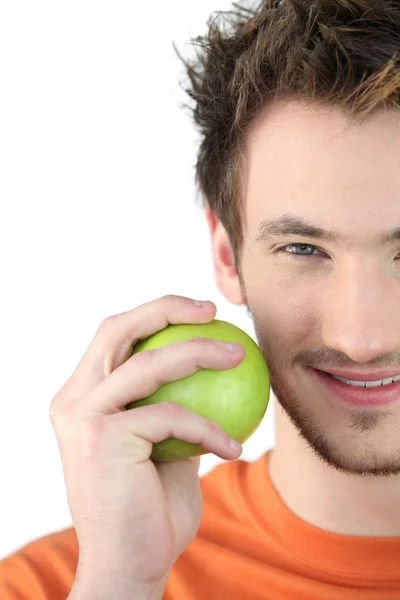 Молодой человек держит зеленое яблоко — стоковое фото