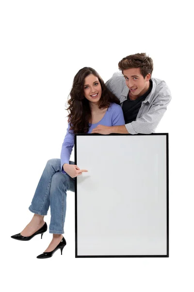 Casal jovem com uma imagem grande deixou em branco para sua mensagem — Fotografia de Stock
