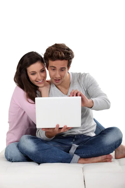 Jovem casal no sofá com laptop — Fotografia de Stock