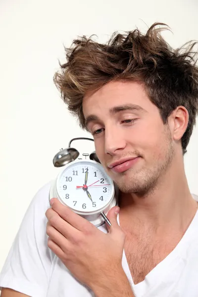 眠そうな男彼の目覚まし時計を抱き締める — ストック写真