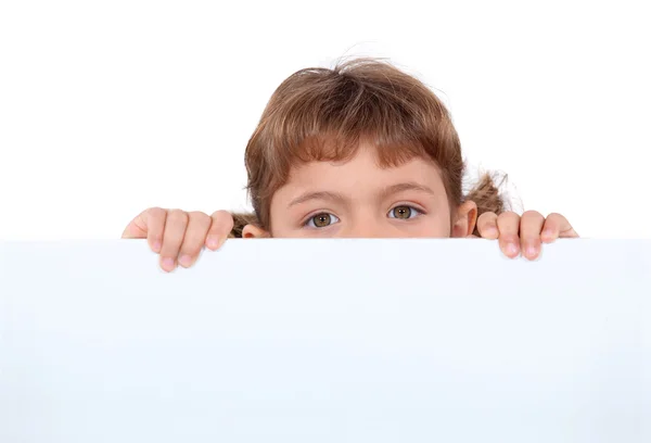 Little girl hiding behind a board — Stock Photo, Image