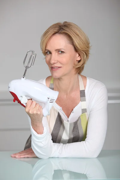 Woman wearing apron holding electric whisk — Stock Photo, Image