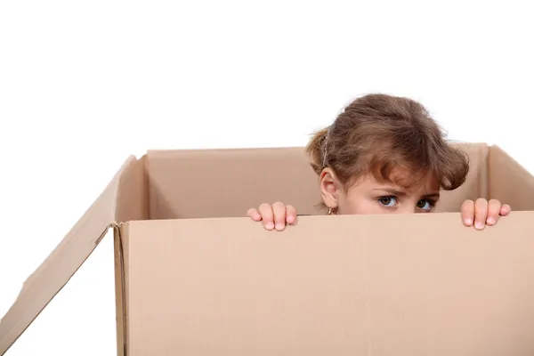 Маленькая девочка играет в картонной коробке — стоковое фото