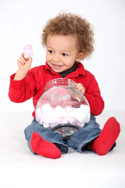 Little boy eating marshmallows from jar — Stock Photo, Image
