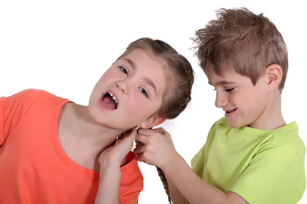 Irmão puxando o cabelo da irmã — Fotografia de Stock