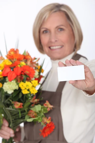 Floristin mittleren Alters reicht Visitenkarte — Stockfoto