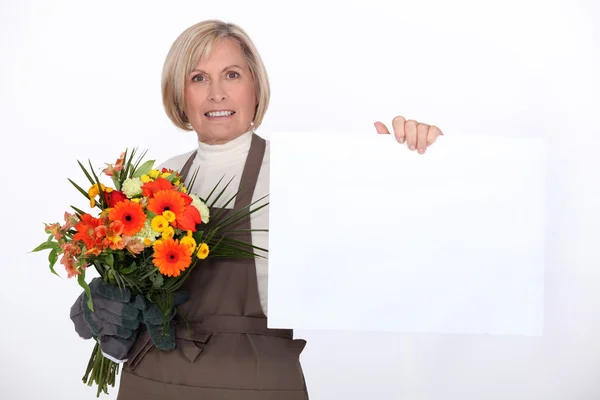 Florist with a bouquet and a board left blank for your message — Stock Photo, Image