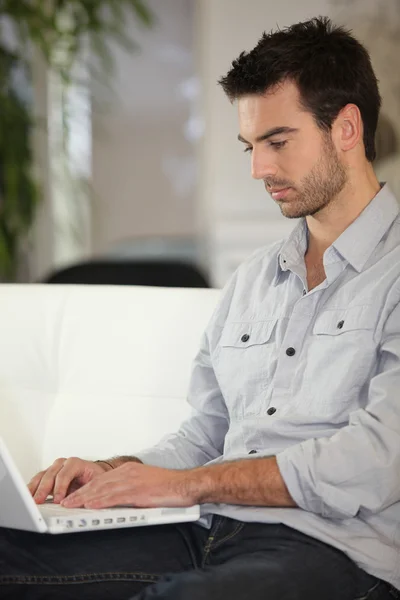 Man sitting on couch with computer Stock Photo