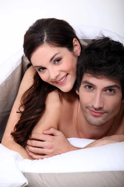 Couple in bed embracing Royalty Free Stock Images