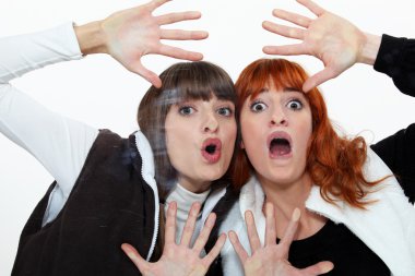 Two friends pressing their face on a pane. clipart