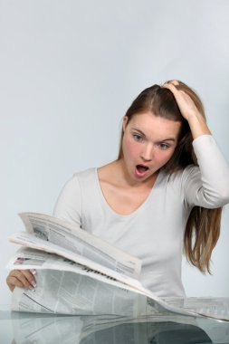 Shocked woman reading a newspaper clipart